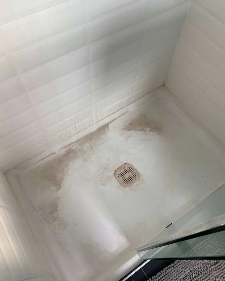 A shower base stained around the drain.
