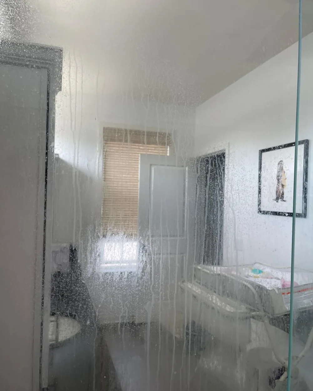 A glass shower panel clouded with soap and hard water.